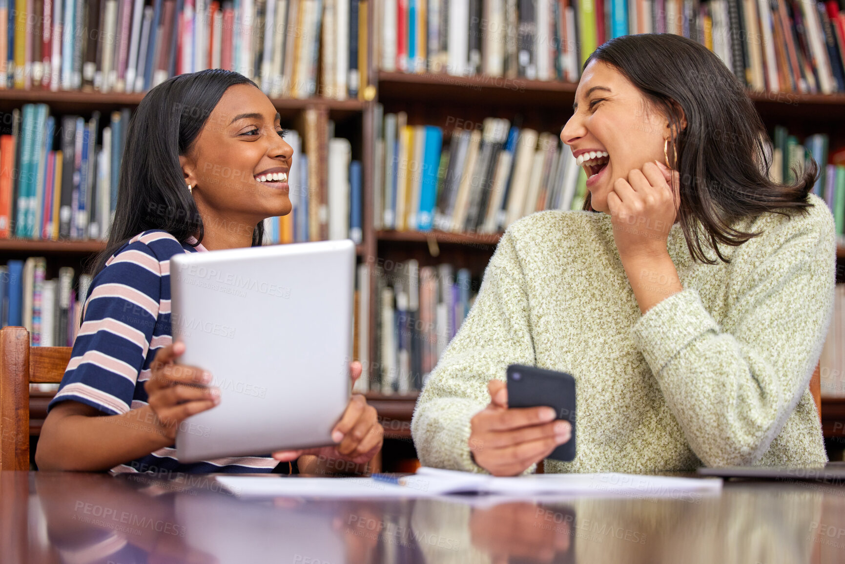 Buy stock photo Shot of two females using their  devices in a library