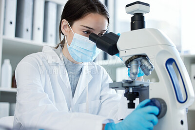 Buy stock photo Shot of a young woman using a microscope in a lab