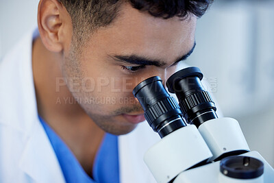 Buy stock photo Shot of a young man using a microscope in a lab