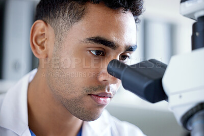 Buy stock photo Shot of a young man using a microscope in a lab