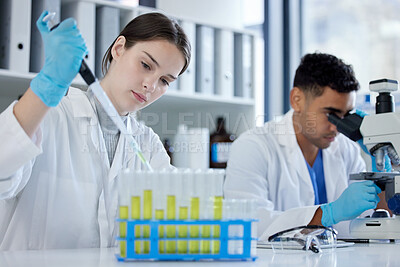 Buy stock photo Shot of a young woman using a dropper and test tube while working with samples in a lab alongside a colleague
