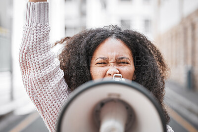 Buy stock photo Shot of a young woman screaming into a loud speaker while protesting in the city