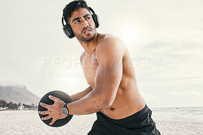 Buy stock photo Shot of a sporty young man wearing headphones while exercising outside with a medicine ball