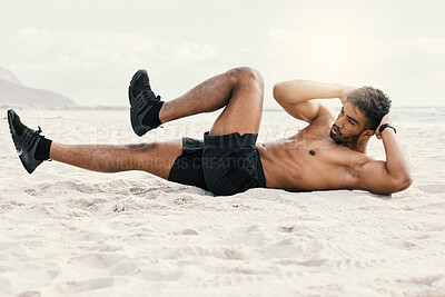 Buy stock photo Shot of a sporty young man doing crunches while at the beach for a workout