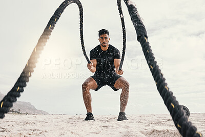 Buy stock photo Shot of a sporty young man exercising outside with heavy ropes