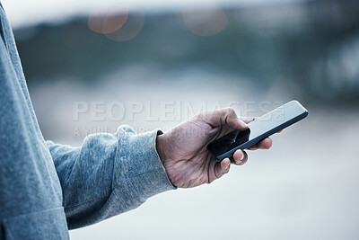 Buy stock photo Cropped shot of an unrecognizable man using his cellphone while standing outside