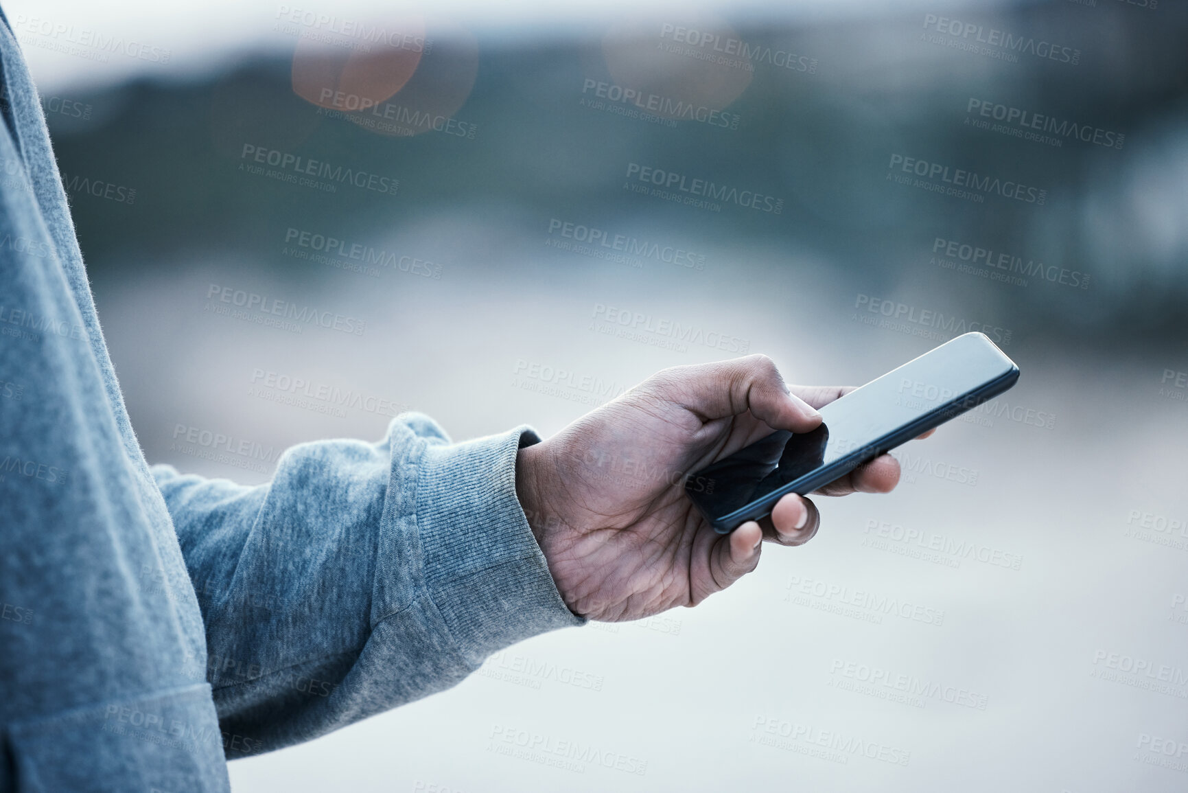 Buy stock photo Cropped shot of an unrecognizable man using his cellphone while standing outside