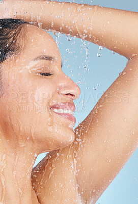 Buy stock photo Studio shot of an attractive young woman taking a shower against a blue background
