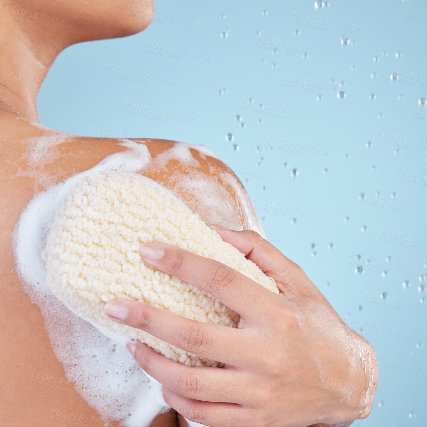 Buy stock photo Hand, sponge and shower with foam in studio for hygiene, bacteria and dirt on back by blue background, Woman, person and model with loofah, soap or water drops with cleaning healthy body for skincare