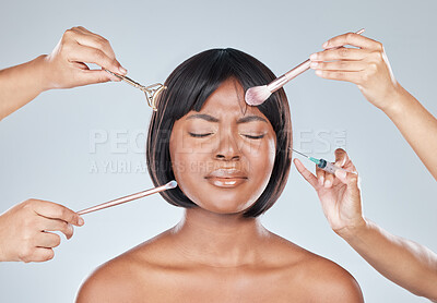 Buy stock photo Studio shot of an attractive young woman having makeup applied to her face and looking unhappy against a grey background