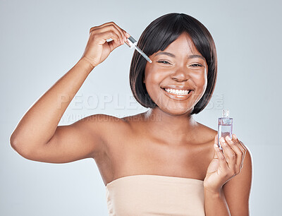 Buy stock photo Studio shot of an attractive young woman applying serum to her face against a grey background