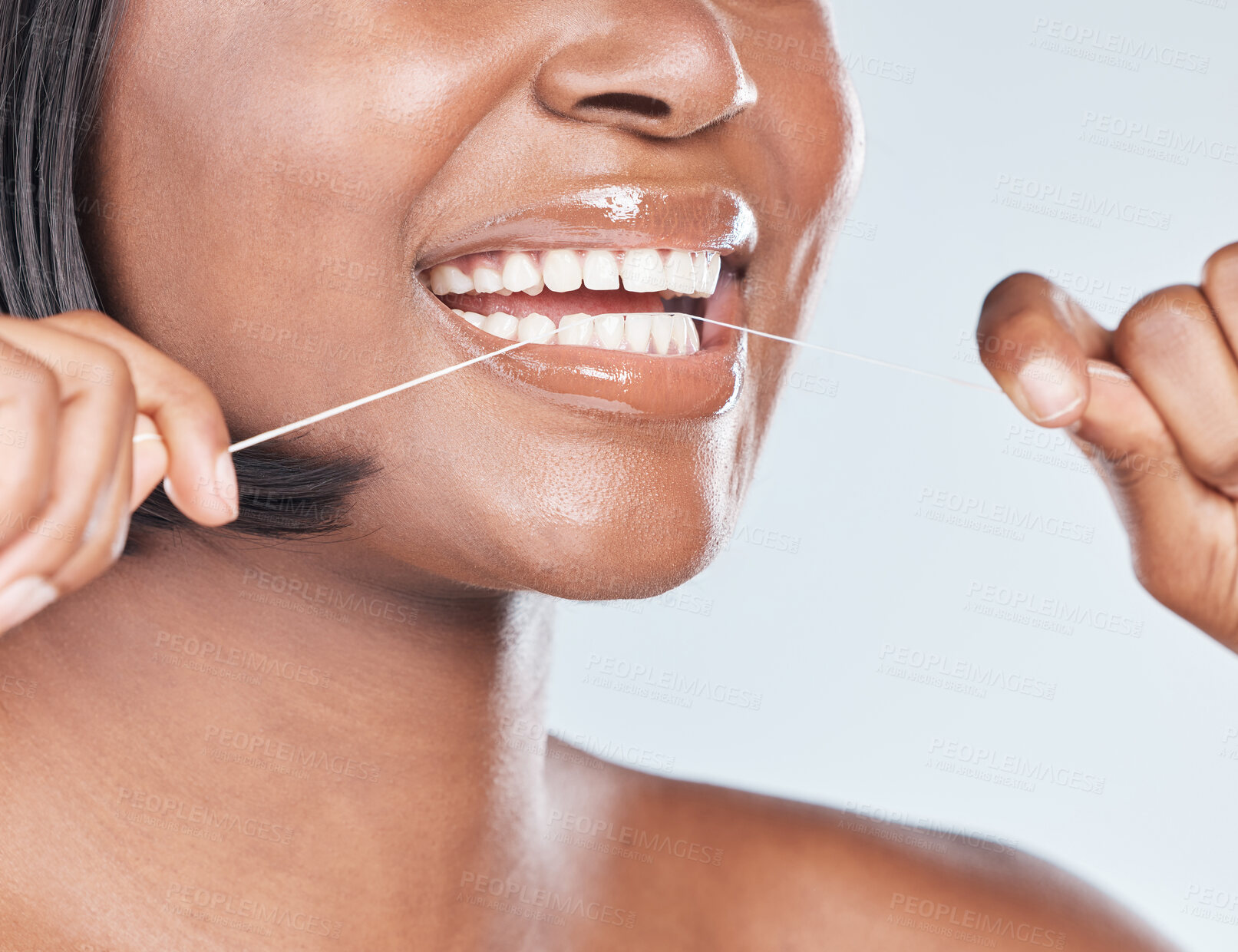 Buy stock photo Studio shot of an attractive young woman flossing her teeth against a grey background