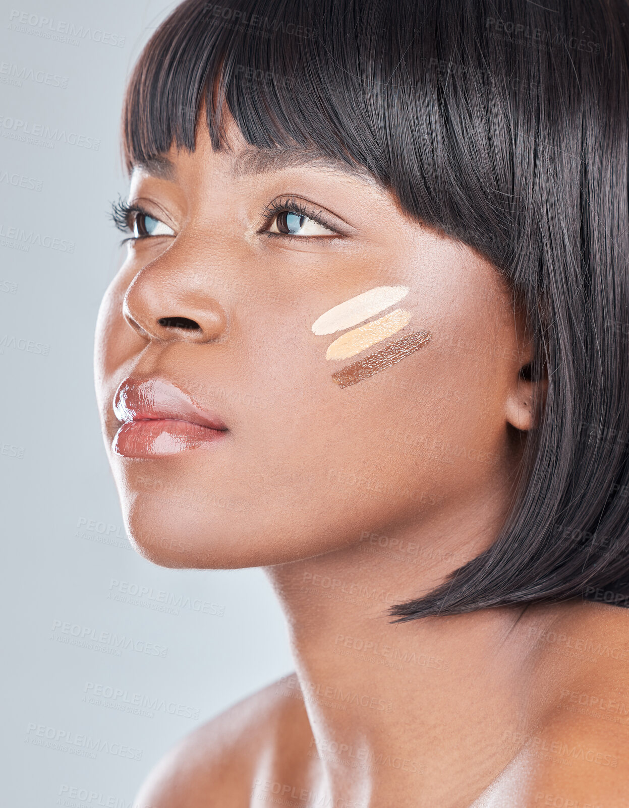 Buy stock photo Studio shot of an attractive young woman applying different shades of foundation to her face against a grey background