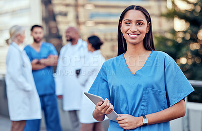 Buy stock photo Shot of a young female doctor using a digital tablet in the city