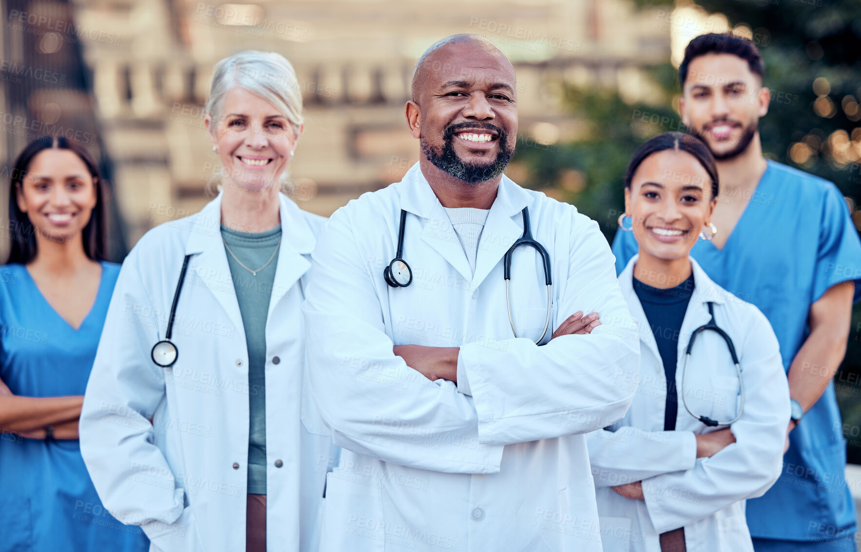 Buy stock photo Shot of a group of doctors standing with their arms crossed in the city