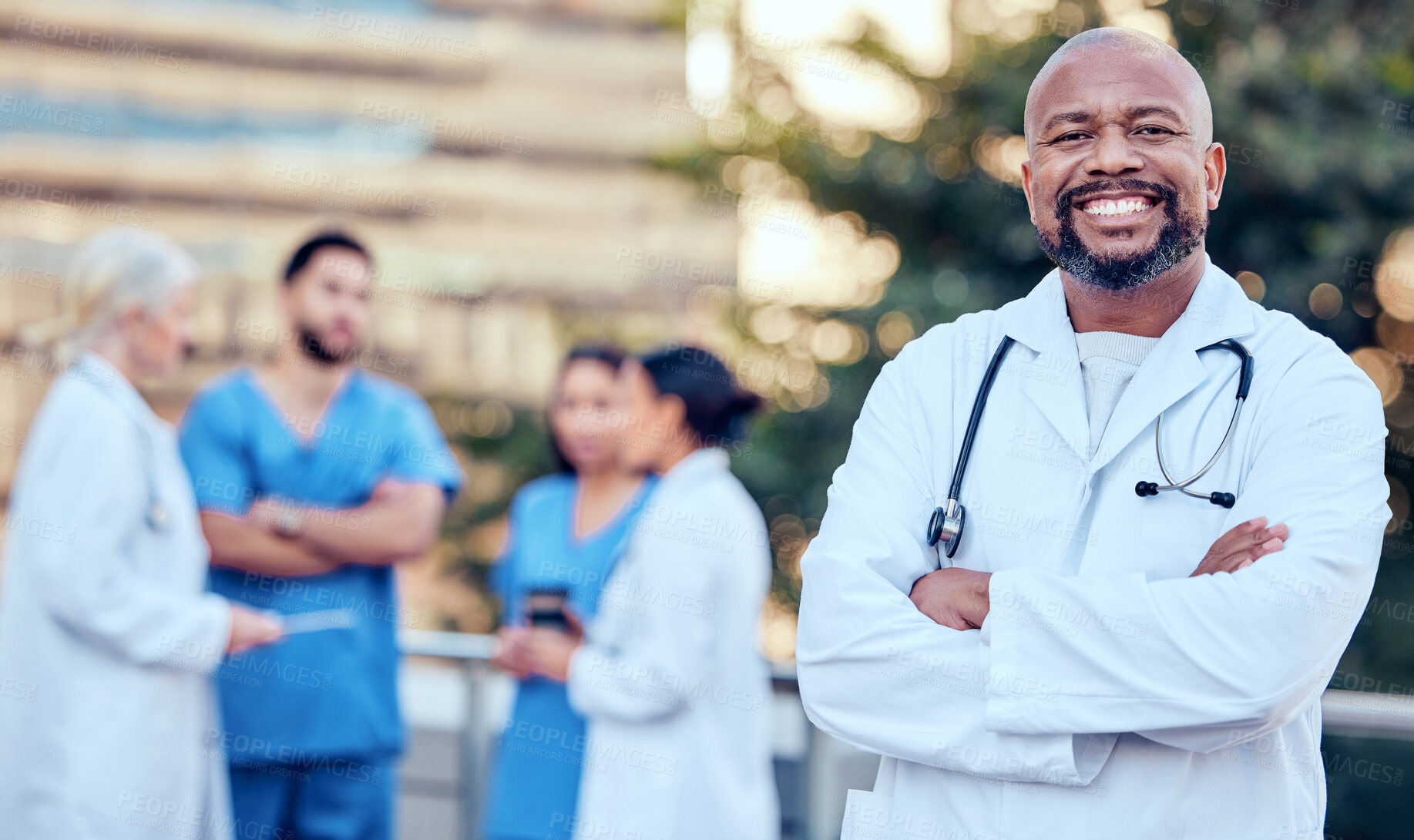 Buy stock photo Shot of a mature male doctor standing with her arms crossed in the city