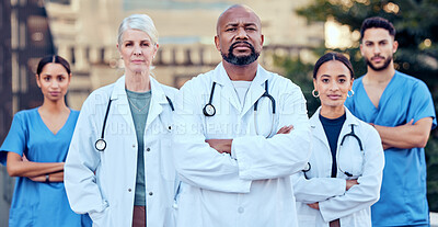 Buy stock photo Shot of a group of doctors standing with their arms crossed in the city