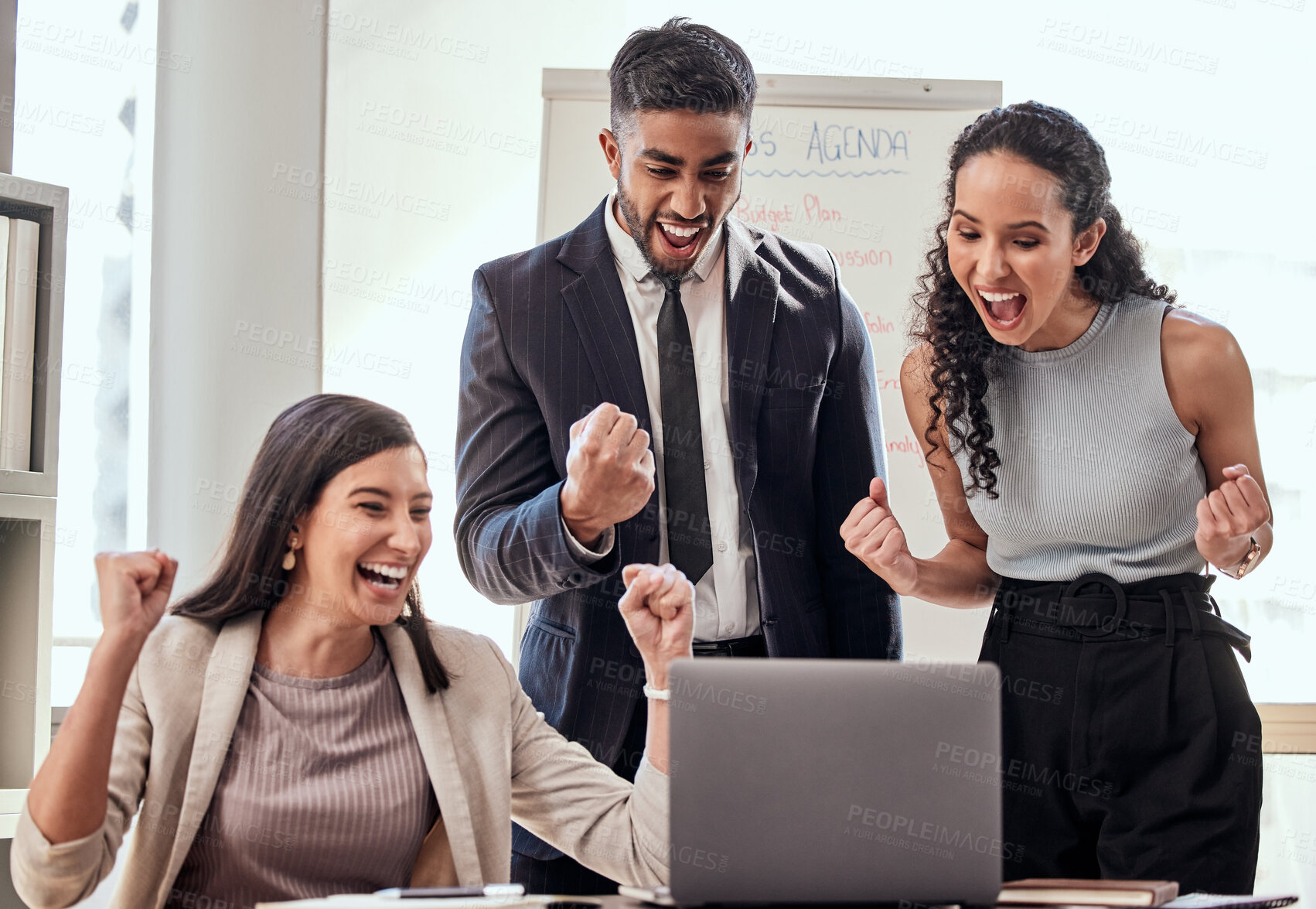 Buy stock photo Shot if a group of young businesspeople cheering while using a laptop at work