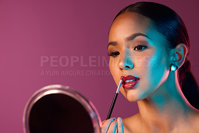 Buy stock photo Woman, makeup artist and lipstick in mirror with neon lights in studio for beauty and art deco. Female person, cosmetics and pride for futuristic, design and creative by pink backdrop with glow 