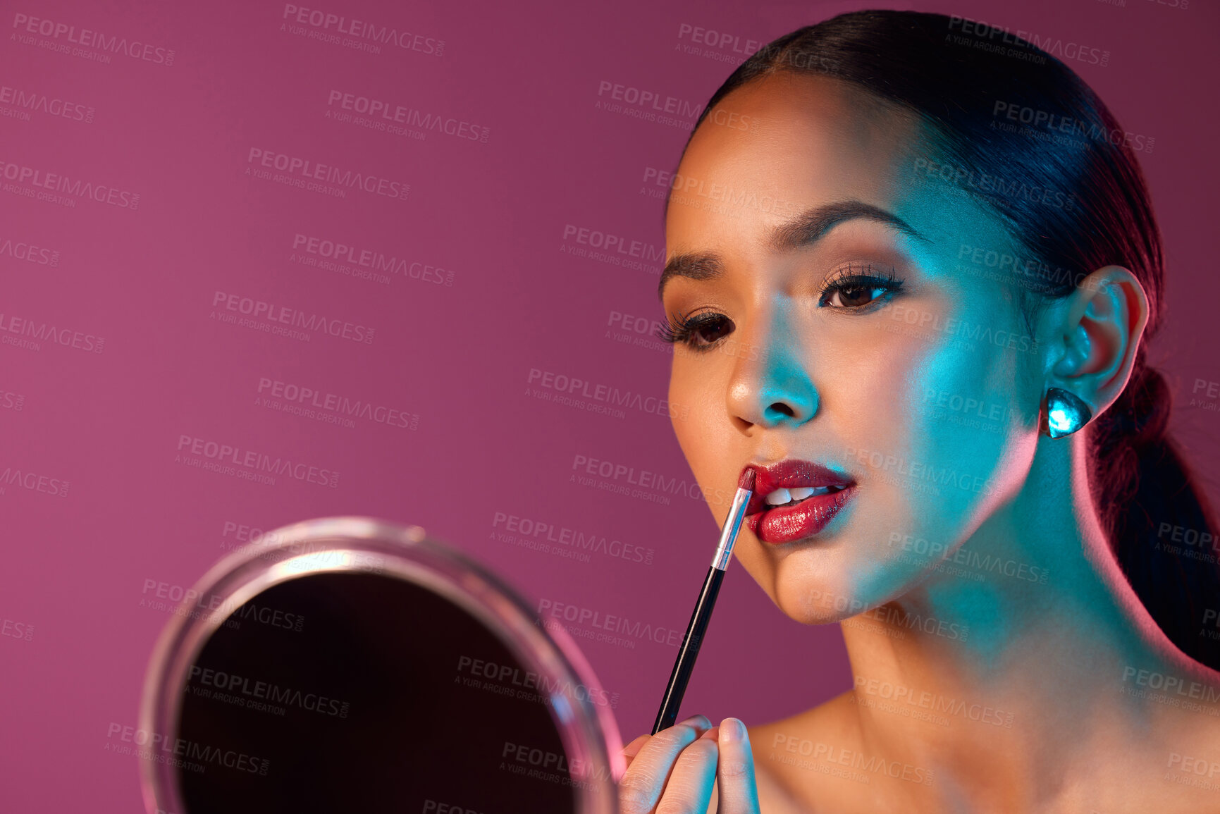 Buy stock photo Woman, makeup artist and lipstick in mirror with neon lights in studio for beauty and art deco. Female person, cosmetics and pride for futuristic, design and creative by pink backdrop with glow 