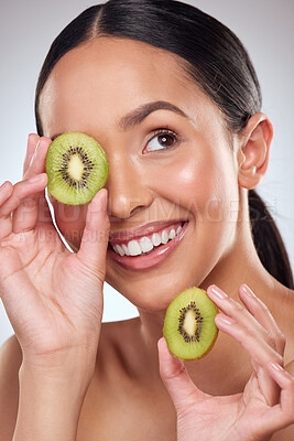 Buy stock photo Studio shot of a beautiful young woman posing with kiwi against a grey background