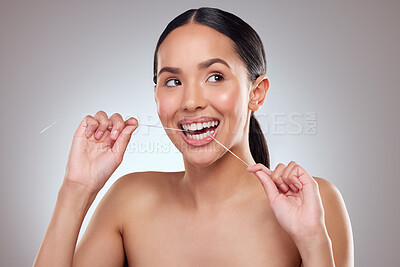 Buy stock photo Studio shot of a beautiful young woman flossing her teeth against a grey background