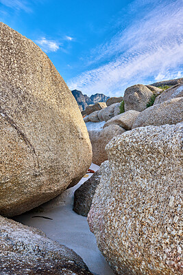 Buy stock photo Big rocks on the beach with a blue sky background on a summer day. A landscape of large or huge boulders on the ocean shore of a remote location. Seaside with huge stones on the sand