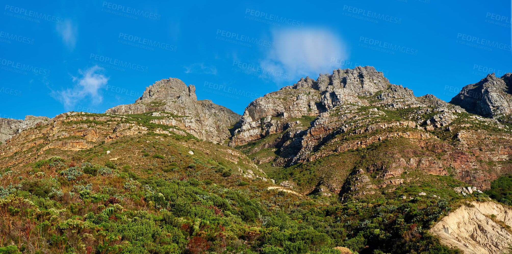 Buy stock photo Below view of majestic mountains with bushes, greenery and cloudy blue sky copy space above. Nature landscape of mountain rock outcrops with wild green plants during a bright and beautiful day