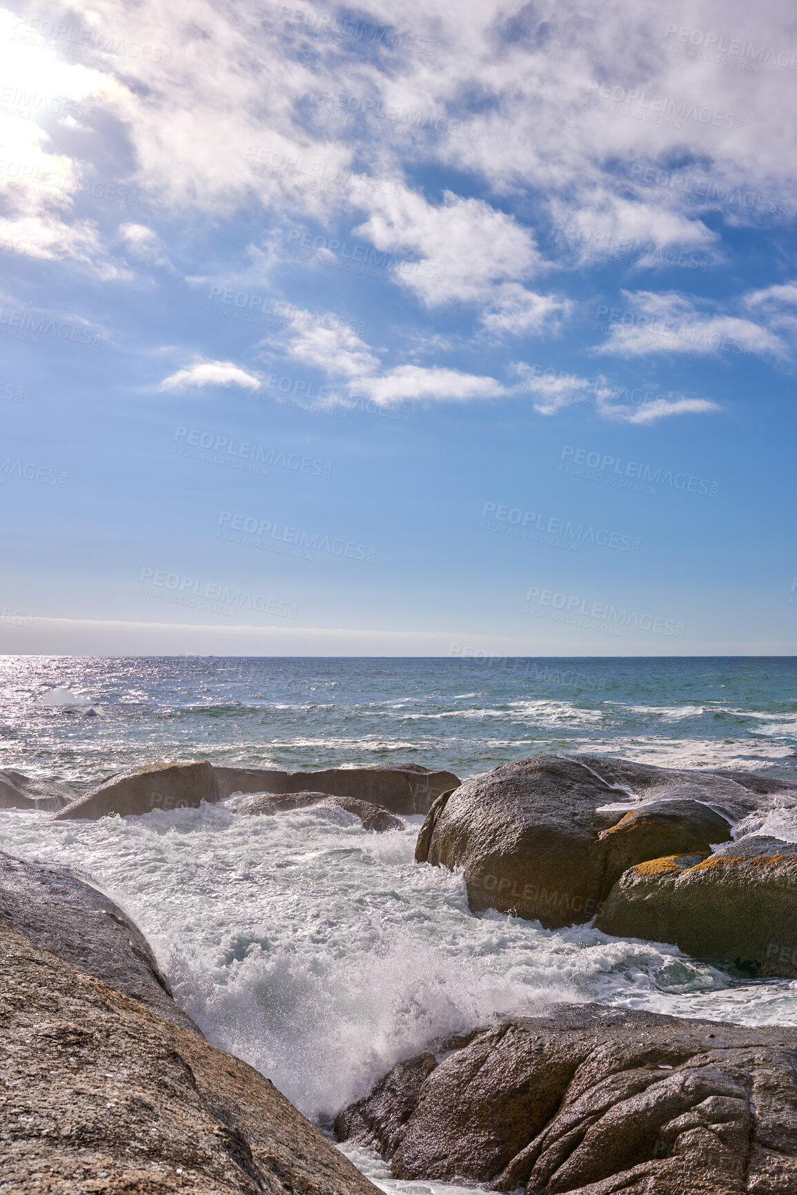 Buy stock photo Waves crashing against rocks in the ocean under a blue cloudy sky with copy space. Scenic landscape of boulders or big stones in the sea at a popular summer location in Cape Town, South Africa