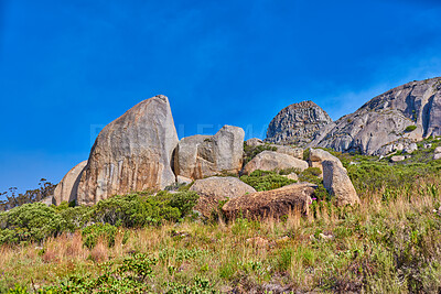 Buy stock photo Copy space on a rocky mountain with plants and shrubs growing against a clear sky background. Rugged, remote and quiet landscape with boulders and stones on a cliff to explore during a scenic hike