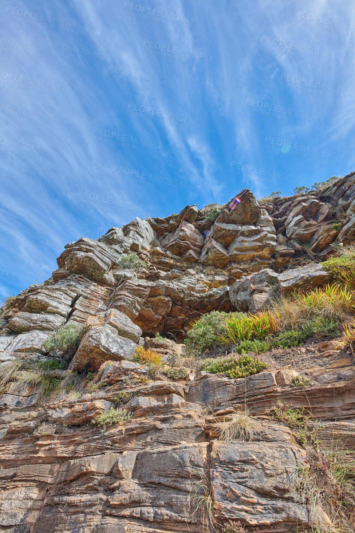 Buy stock photo Large stones in the mountains for outdoor climbing with a blue sky background in a natural environment. Big rocks, plants, and green grass from below. Scenic view of a large natural mountainside 