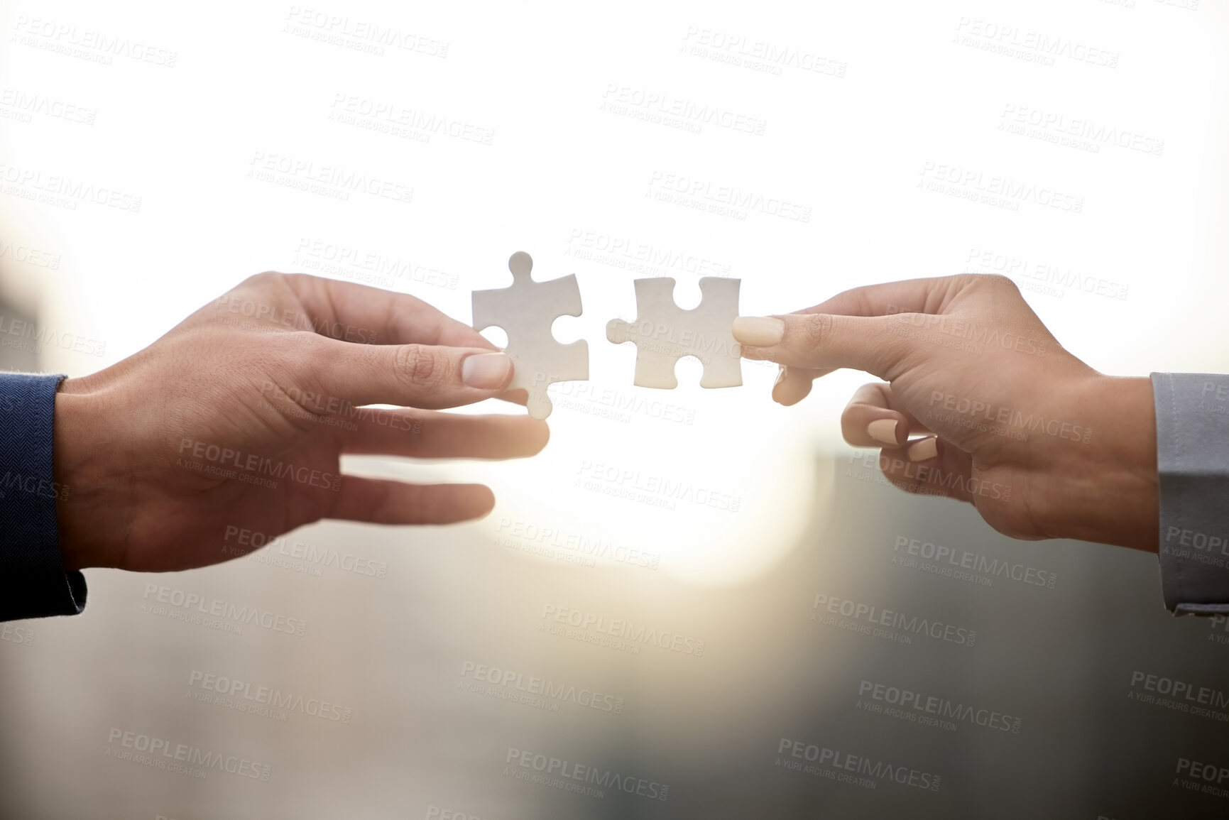 Buy stock photo Shot of two unrecognizable people holding up puzzle pieces against a city background