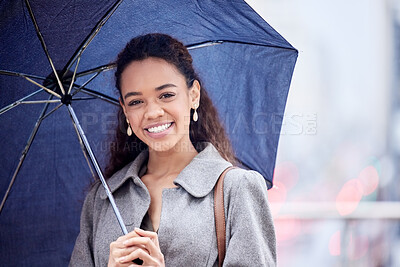 Buy stock photo Shot of a young businesswoman carrying an umbrella in the rain