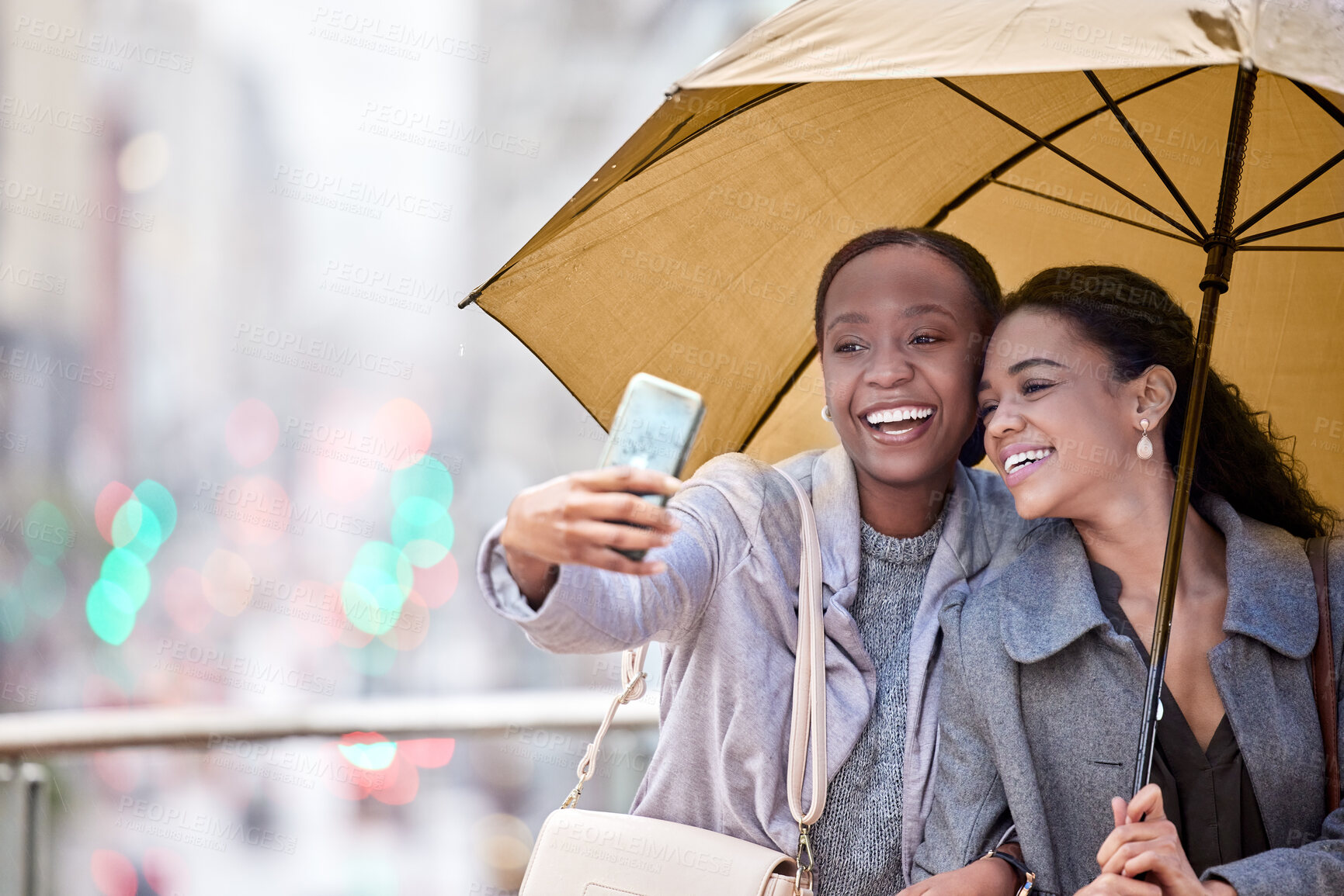 Buy stock photo Shot of two young friends taking a selfie in the rain