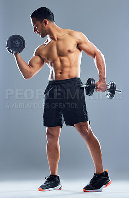 Buy stock photo Studio shot of a muscular young man exercising with dumbbells against a grey background
