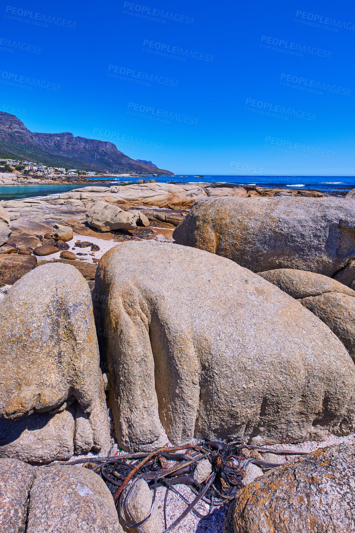 Buy stock photo Scenic view of the rocky coastline of Camps Bay, Cape Town. Boulders in lining the ocean in the Western Cape, South Africa. Relaxing seaside views of the city of and mountains