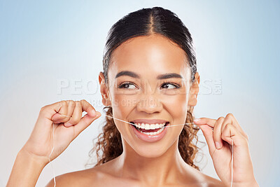 Buy stock photo Shot of a young woman flossing her teeth against a blue background