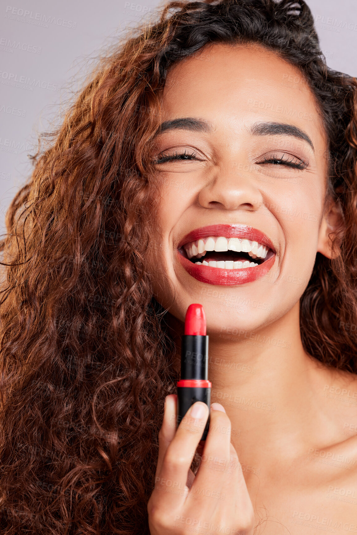 Buy stock photo Shot of a young woman applying lipstick against a grey background