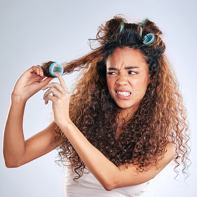 Buy stock photo Cropped shot of an attractive young woman struggling with hair curlers in studio against a grey background