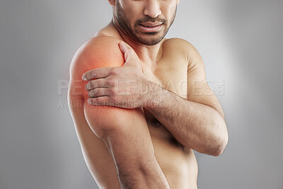 Buy stock photo Cropped studio shot of a muscular young man experiencing shoulder pain against a grey background