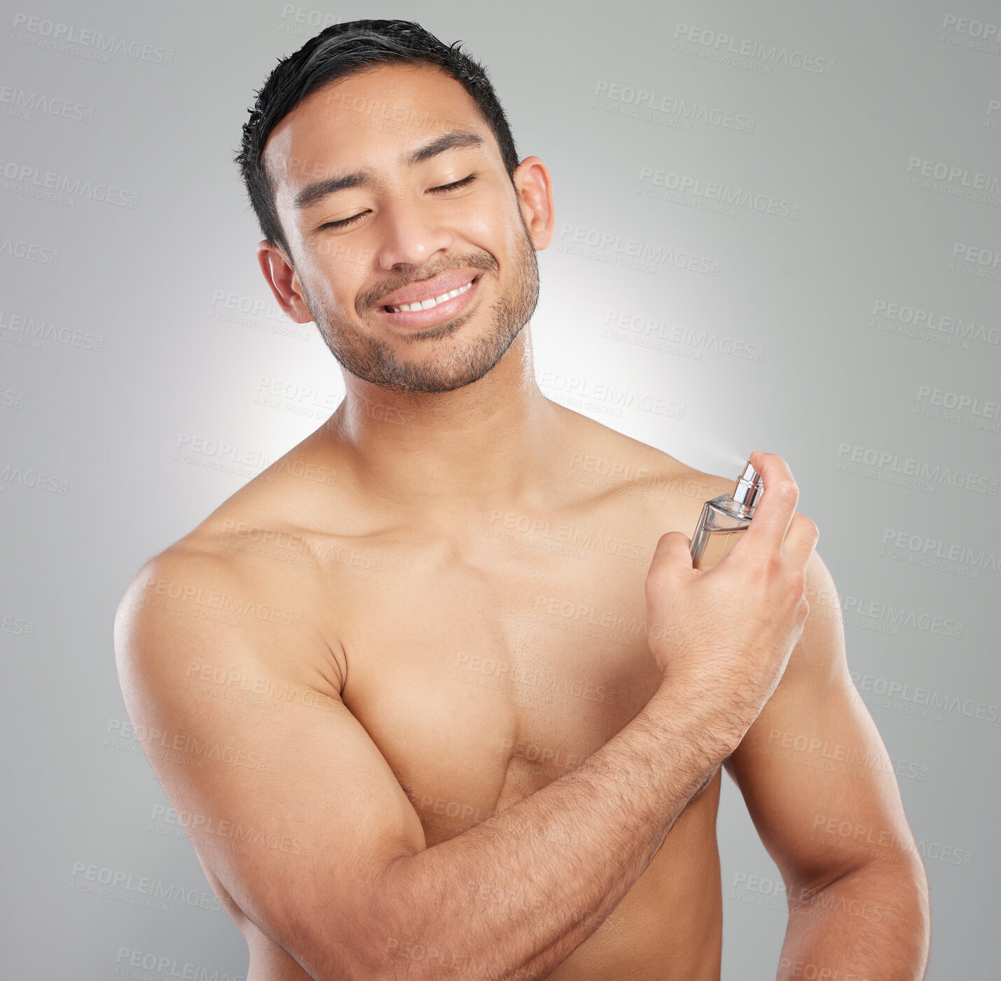 Buy stock photo Studio shot of a handsome young man applying perfume against a grey background