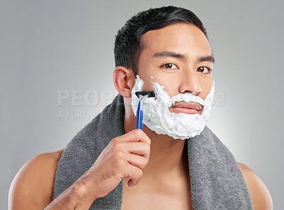 Buy stock photo Studio shot of a handsome young man shaving against a grey background