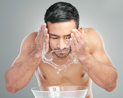Buy stock photo Studio shot of a handsome young man washing his face against a grey background