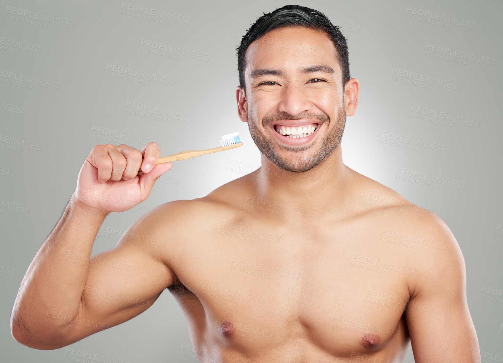 Buy stock photo Studio shot of a handsome young man brushing his teeth against a grey background