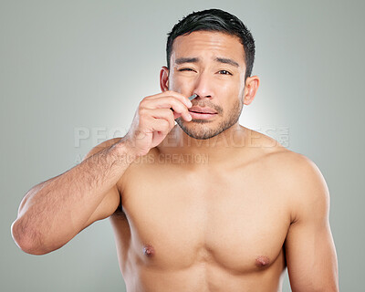 Buy stock photo Studio shot of a handsome young man plucking his eyebrows against a grey background