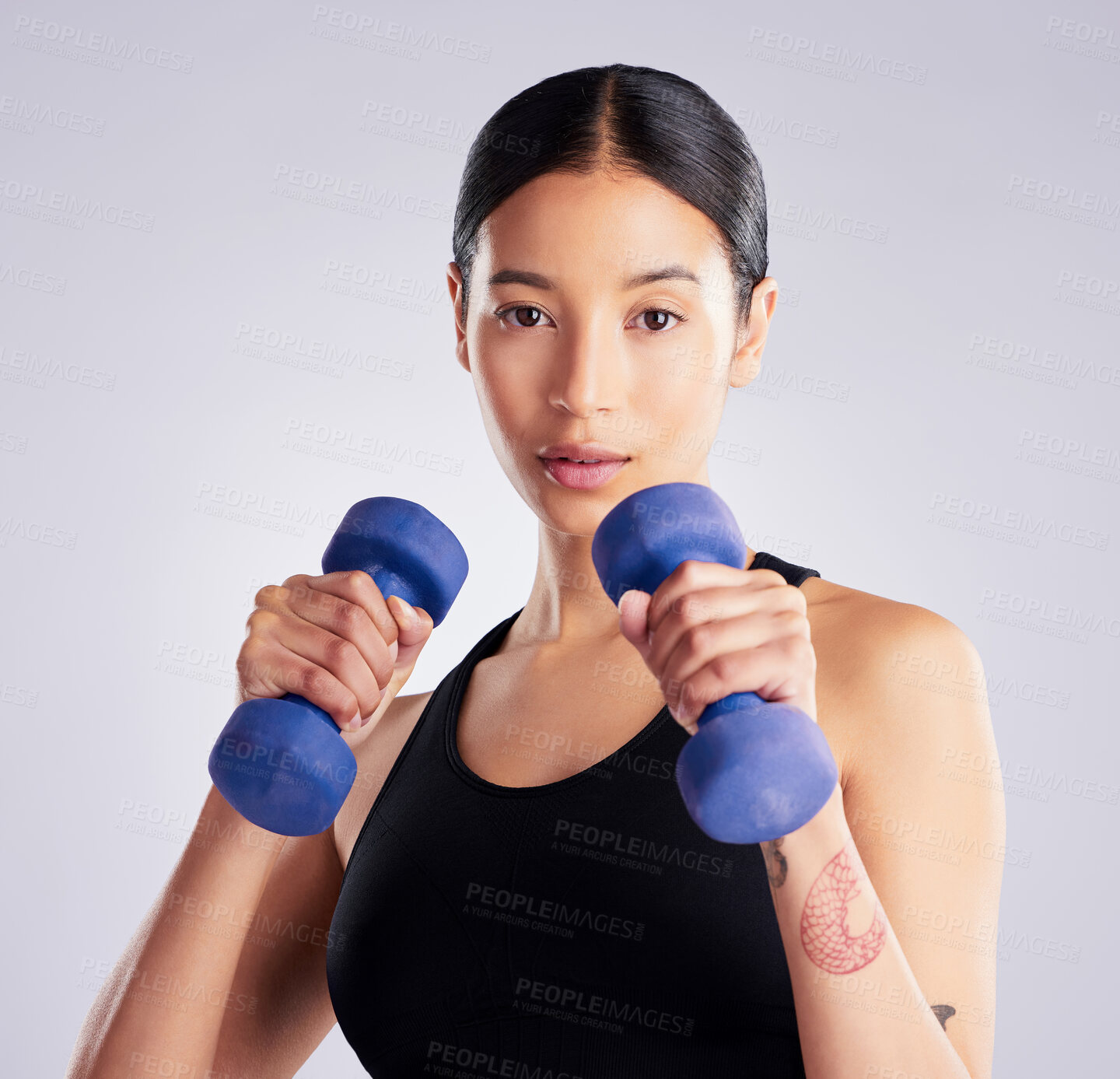 Buy stock photo Shot of an attractive young woman standing and posing with dumbbells during her workout