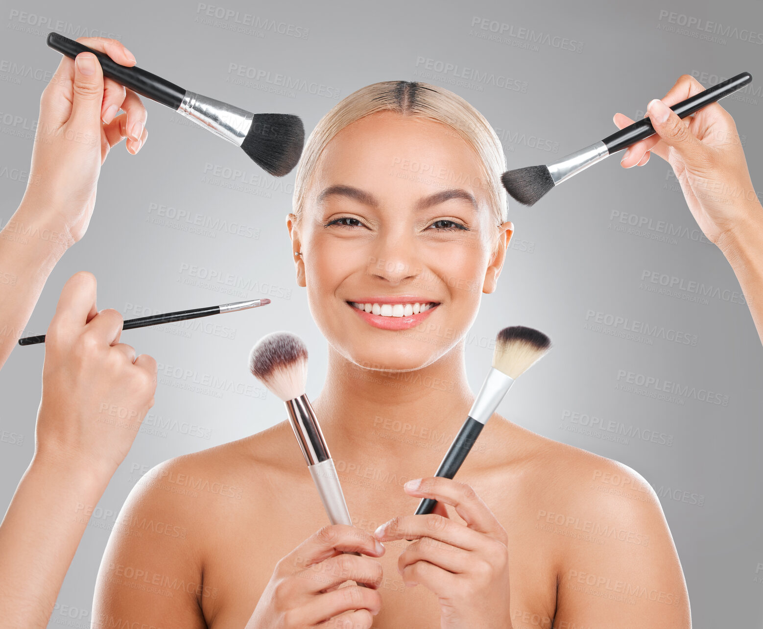 Buy stock photo Shot of an attractive young woman using a makeup brush against a studio background