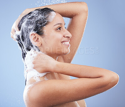 Buy stock photo Shot of a young woman washing her hair in the shower against a blue background