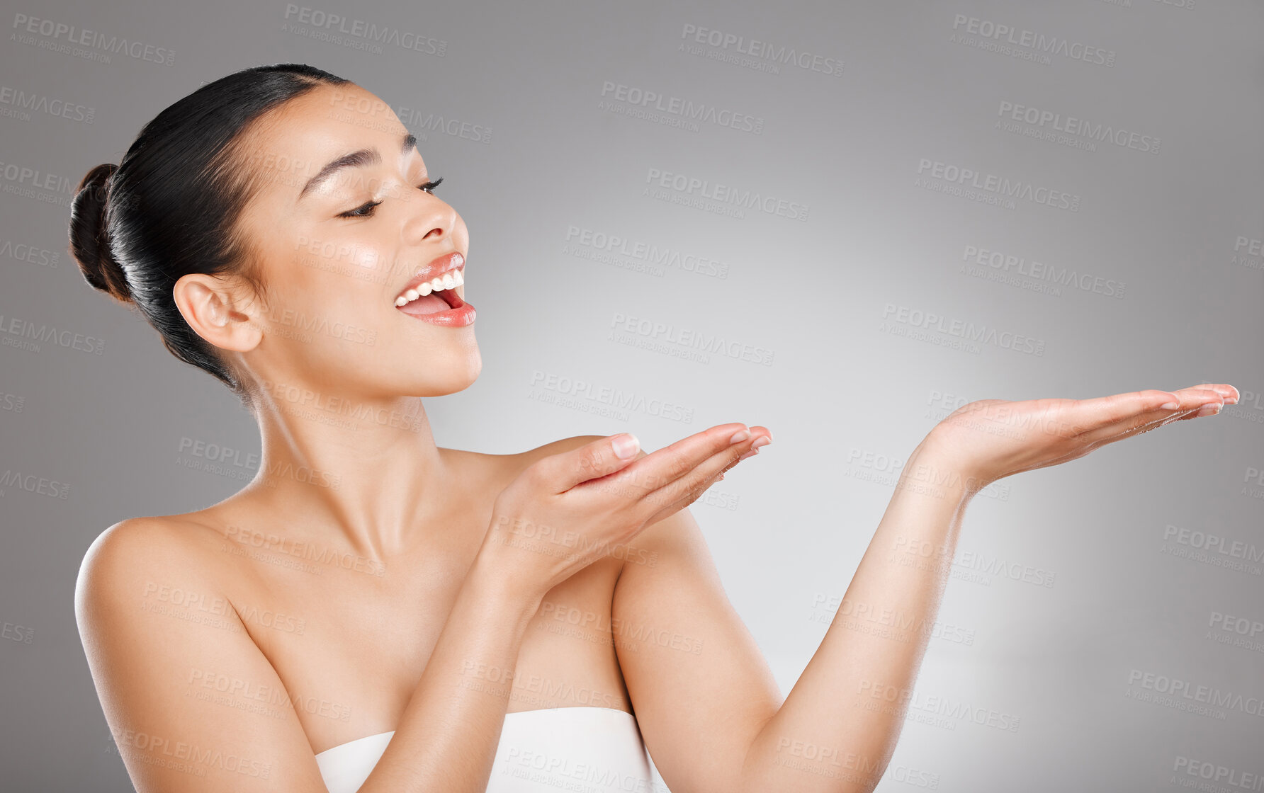 Buy stock photo Studio shot of an young woman pointing at copy space against a grey background