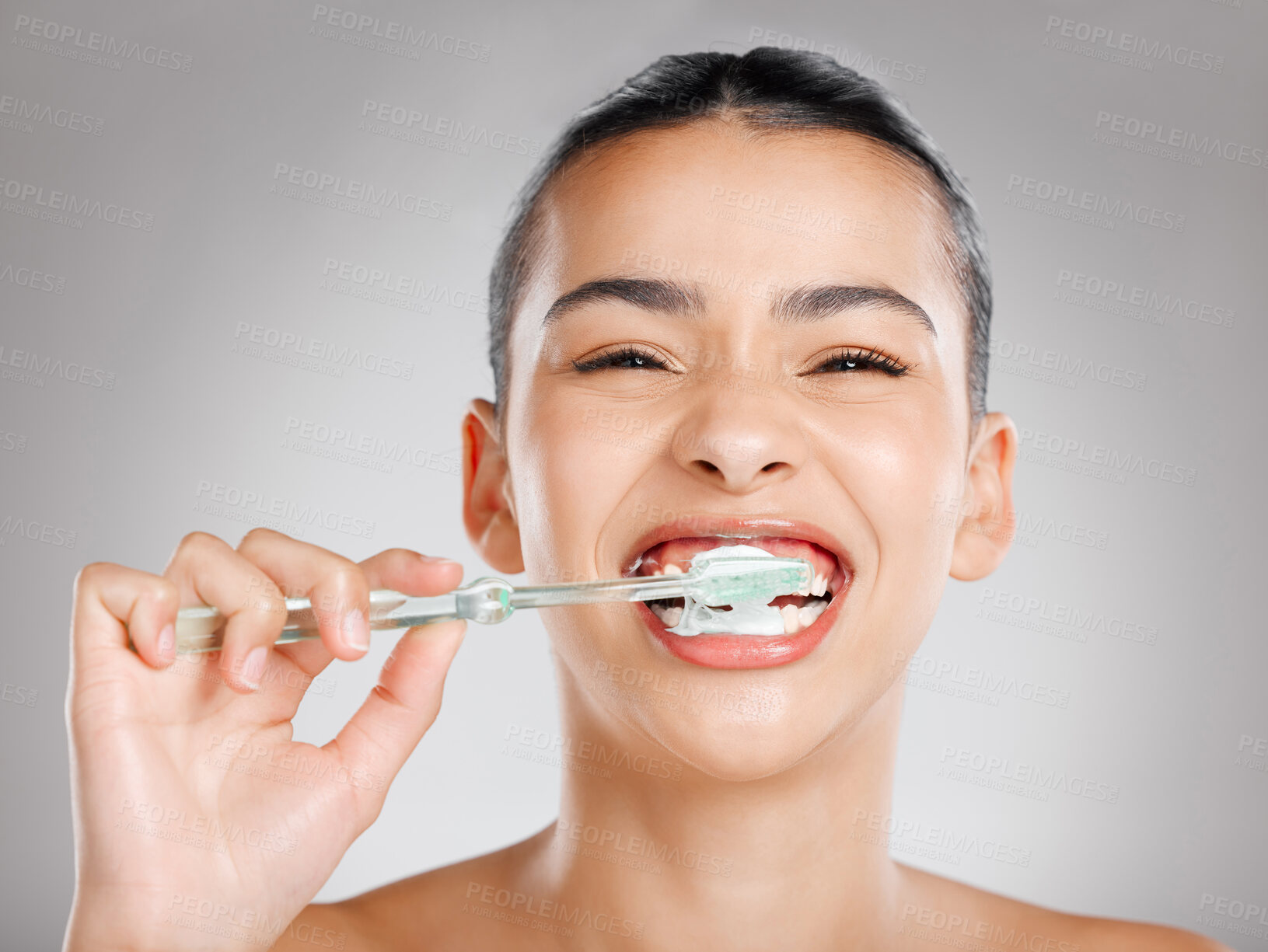 Buy stock photo Studio shot of an attractive young woman brushing her teeth against a grey background